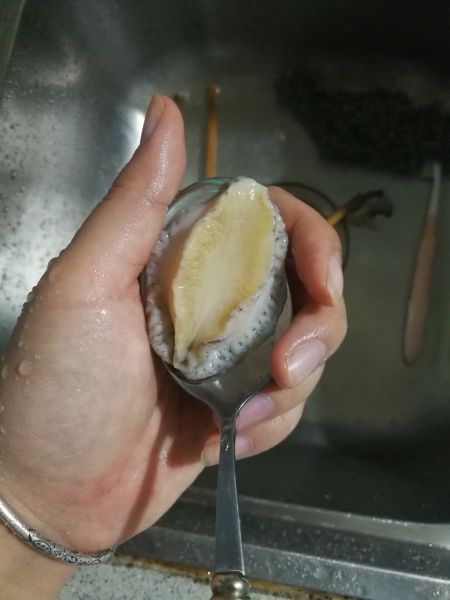 用勺子翘出鲍鱼肉,摘掉肠内脏.